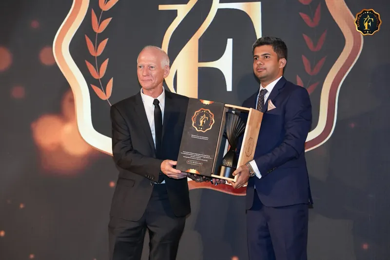 Robbie McKenzie on stage holding the 2025 FLUXX Award trophy in its presentation case